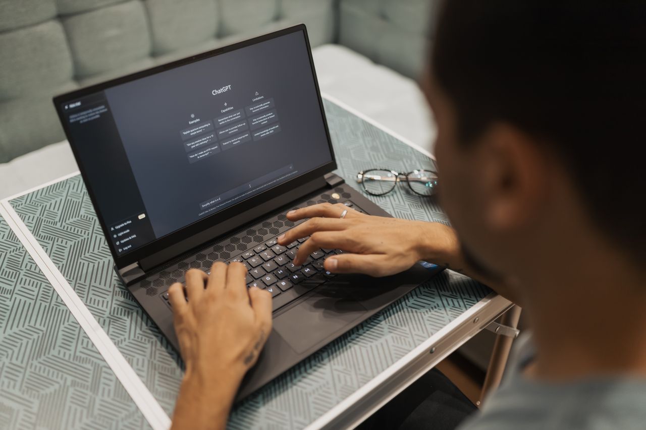 Home A person using a laptop to interact with AI technology indoors during the day.