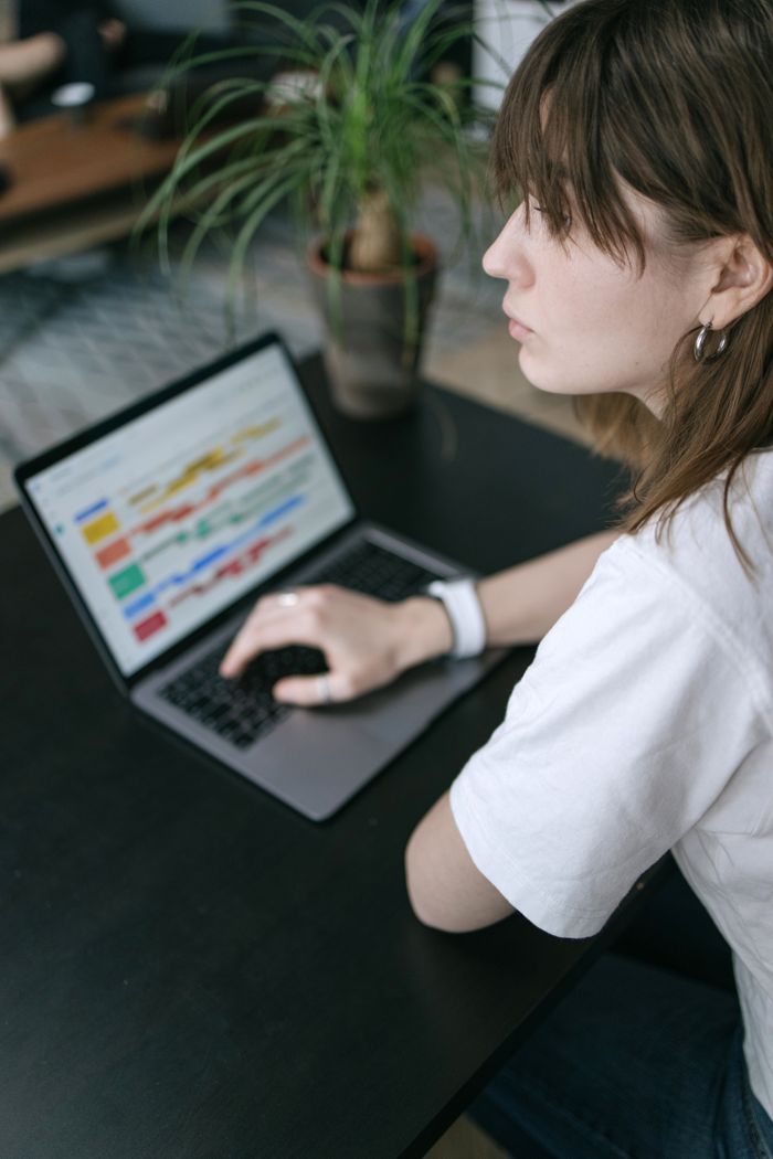 Crafting Captivating Headlines: Your awesome post title goes here A woman studies data charts on her laptop at a modern indoor workspace.